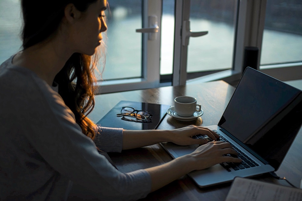 Rilettura e annotazione di un testo durante la revisione - Ragazza scrivendo al computer al tramonto