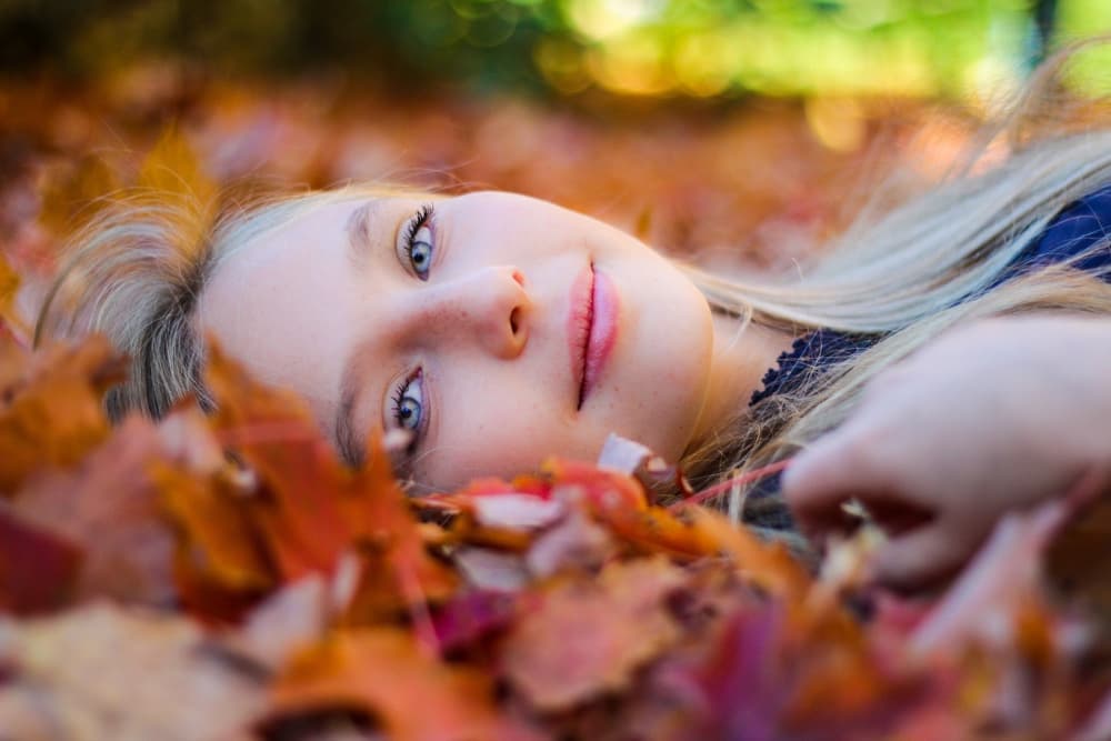 Puoi cambiare il futuro - Ragazza bionda in primo piano distesa tra le foglie autunnali